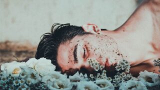 man lying on white flowers